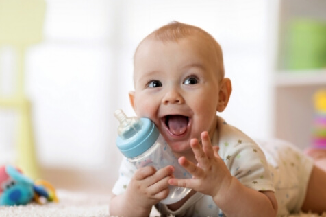 Baby holding bottle and smiling